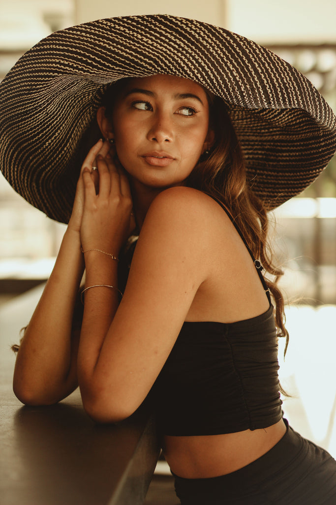 Model wearing 7 inch Wide Brim Black Two Tone Melange Packable Straw Sun Hat handmade loomed raffia in a multicolor heathered melange pattern of black and natural straw color creates a subtle swirl - Shebobo
