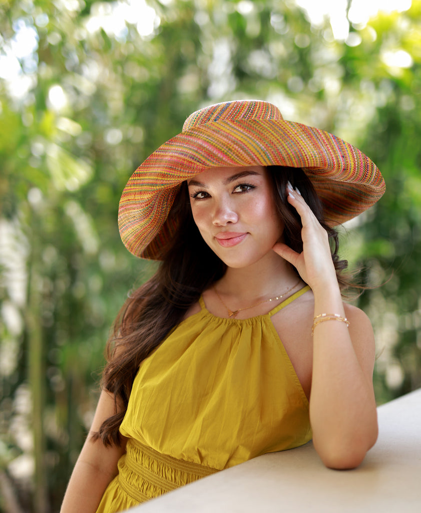 Model wearing 5" Wide Brim Saffron Multi Melange Packable Straw Sun Hat handmade loomed raffia heather swirl pattern of saffron yellow, orange, red, bordeaux, green, pink, blue, etc. - Shebobo
