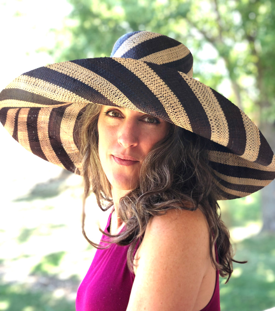 Model wearing 7" Wide Brim Black and Natural Stripe Multicolor Stripe Pattern Packable Straw Sun Hat handmade loomed raffia in bands of black and natural straw color create a striped swirl pattern - Shebobo