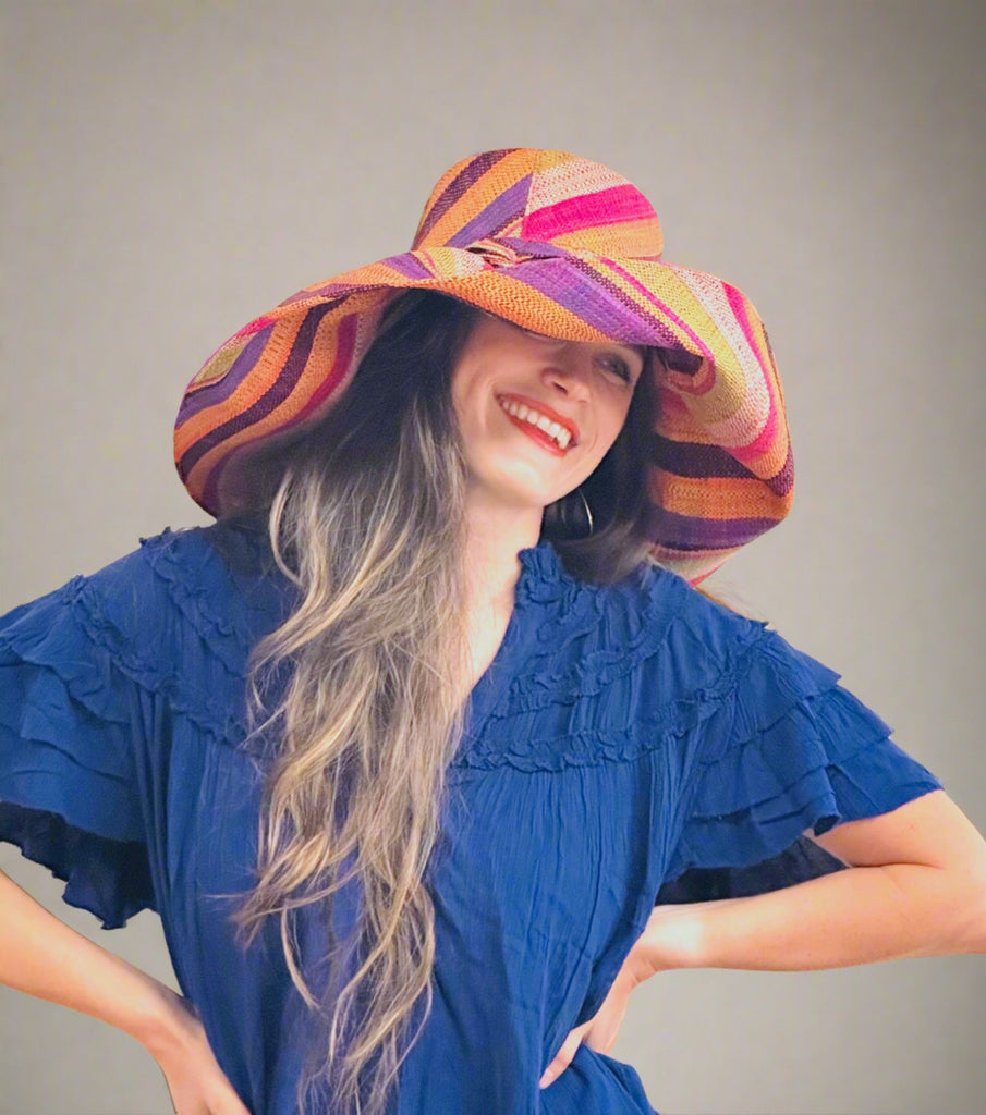 Model wearing 5" & 7" Wide Brim Blue Rainbow Multicolor Stripes Packable Straw Sun Hat Handmade loomed raffia multi width bands of turquoise blue, lime green, fuchsia pink, orange, yellow, purple, black, and natural straw color create a swirl pattern - Shebobo