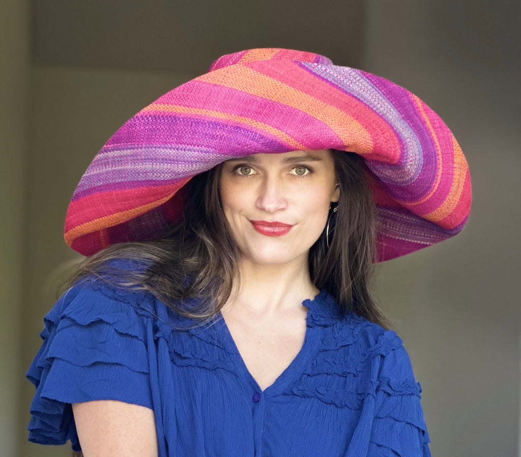 Model wearing 5" & 7" Wide Brim Sherbert Swirl Multicolor Stripes Packable Straw Sun Hat Handmade loomed raffia in multi width bands of saffron yellow, fuchsia pink, blue, purple, orange, red, etc. create a swirl pattern - Shebobo