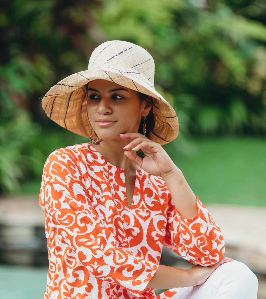 Model wearing 5 inch wide brim natural and black pinstripes packable raffia straw hat handmade loomed raffia in wide bands of natural straw color with black narrow bands create a stripe swirl pattern - Shebobo