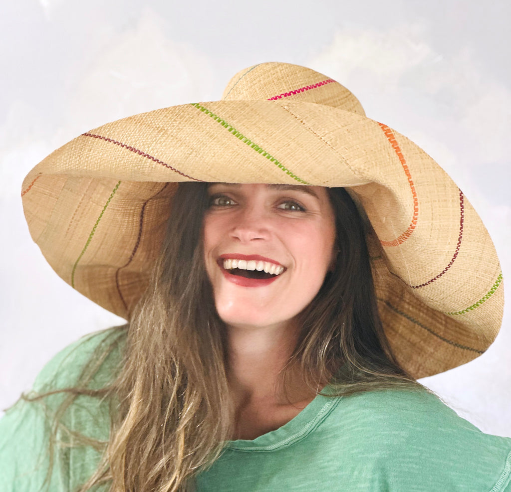 Model wearing 5 inch or 7 inch wide brim natural and multicolor pinstripes packable raffia straw hat handmade loomed raffia in wide bands of natural straw color with narrow bands of lime green, bordeaux red, fuchsia pink, orange, cinnaon/tobacco/brown, blush orange/pink, etc. create a stripe swirl pattern - Shebobo