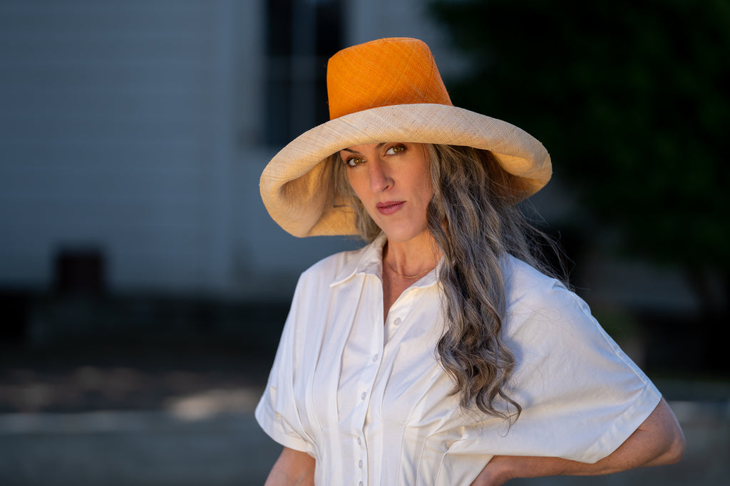 Model wearing 7" Brim Two Tone Saffron Straw Hat handmade loomed raffia color block pattern of the top half saffron orange/yellow and the bottom half natural straw color - Shebobo