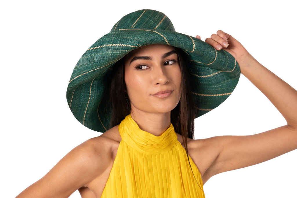 Model wearing 5" Wide Brim Teal Pinstripes Packable Straw Sun Hat handmade loomed raffia in wide stripes of teal dark/green/blue with narrow stripes of natural creating a swirl pattern - Shebobo