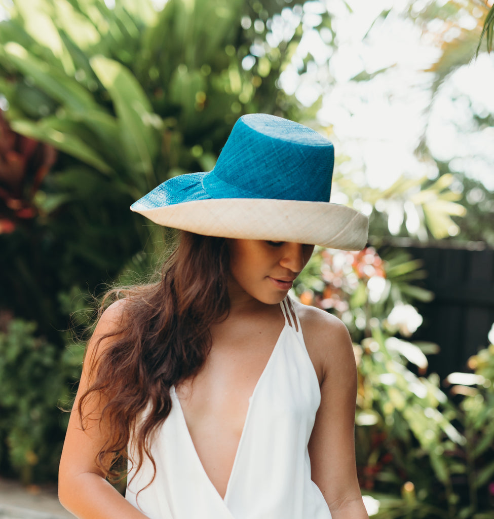 Model wearing 5 inch wide brim two tone turquoise blue and natural packable raffia straw hat handmade loomed raffia with a solid hue of turquoise blue on the top half, and natural straw color on the bottom half - Shebobo