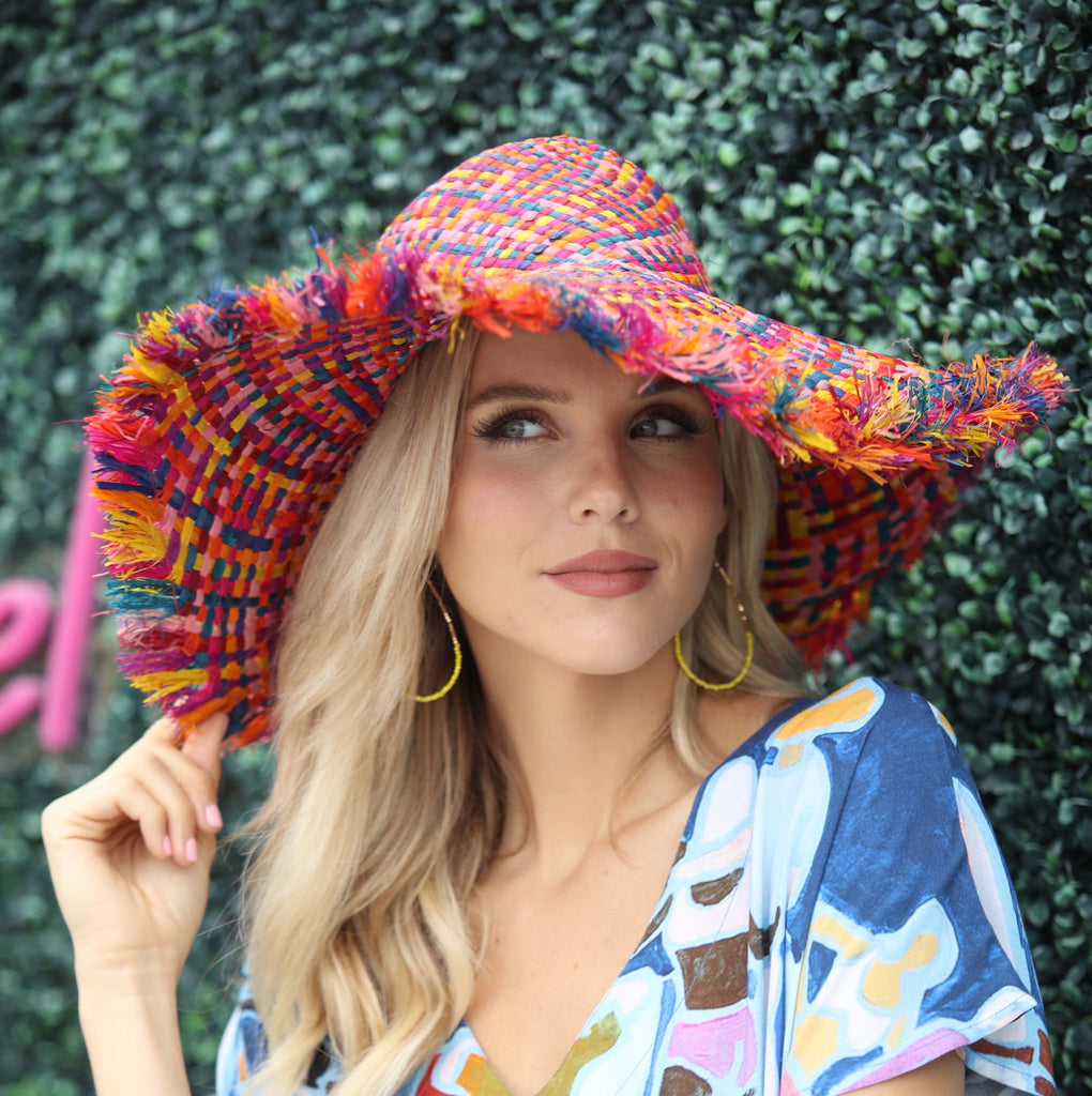 Model wearing 5" Brim Kat Raspberry Multi Multicolor Straw Sun Hats with Raw Fringe Edge handmade woven raffia in a crosshatch pattern of fuchsia pink, yellow, pink, caramel brown, purple, blue, bordeaux, turquoise, black, orange, and natural straw color with wide brim and hand brushed edge embellishment - Shebobo