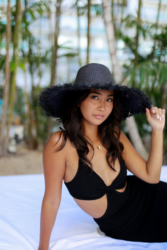 Model wearing 5" Brim Kat Black Solid Colors Straw Sun Hat with Raw Fringe Edge handmade woven raffia in a solid hue of black with wide brim and hand brushed edge embellishment - Shebobo