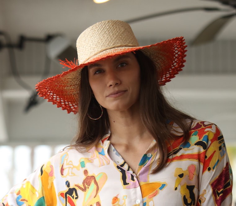 Model wearing 5" Brim Vanessa Ombre Straw Sun Hat Coral and Natural handmade dip dye woven raffia with the color on the outer edge of the hat brim woven into natural as it progresses towards the inner brim with solid natural on the crown and detailed zig zag edging - Shebobo