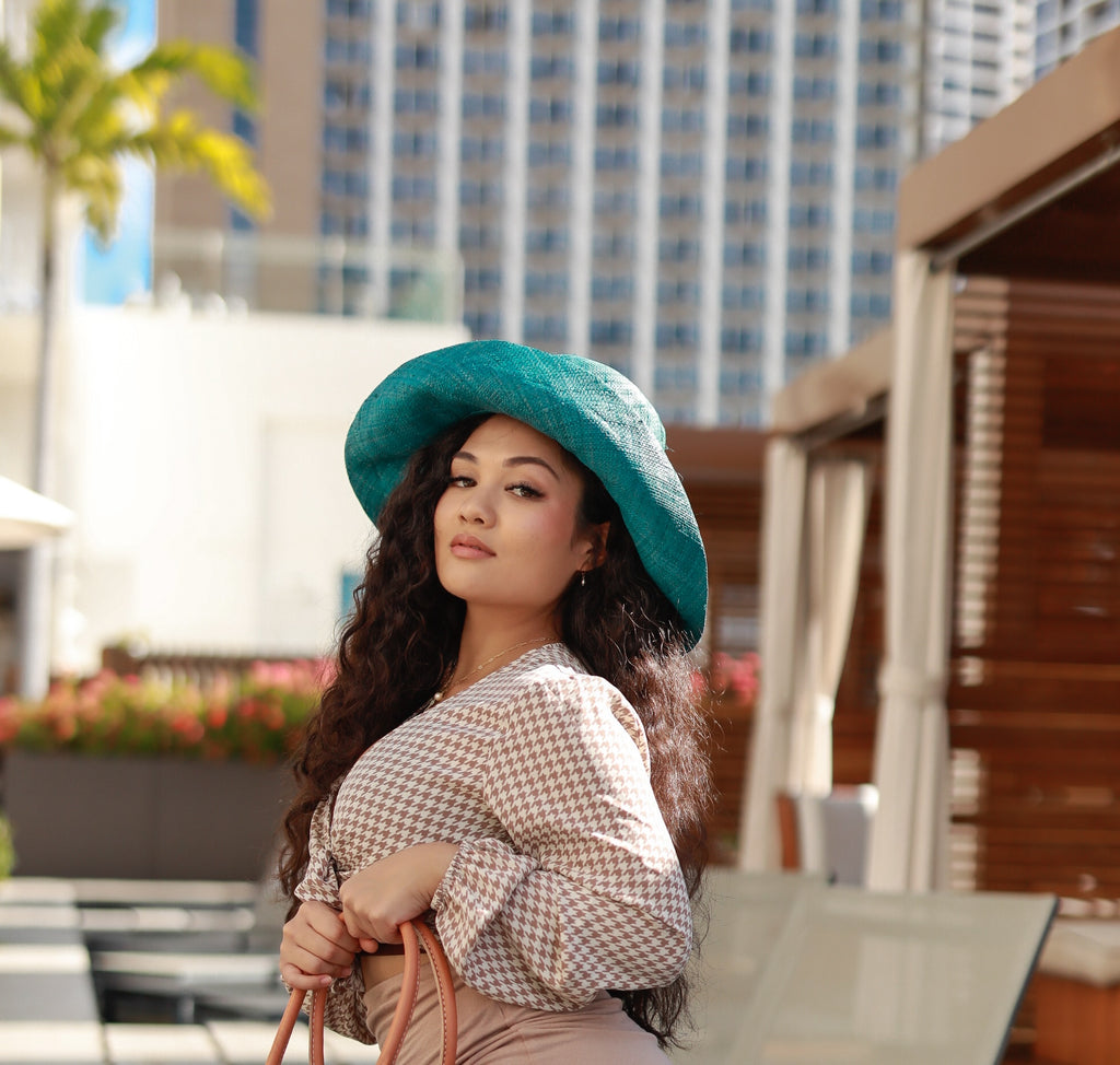 Model wearing 5" Wide Brim Natural Packable Straw Sun Hat handmade loomed raffia in a solid hue of teal lightweight malleable flexible sun protection hat - Shebobo