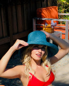 Model wearing 5"  Wide Brim Turquoise Packable Straw Sun Hat handmade loomed raffia in a solid hue of turquoise blue lightweight malleable flexible sun protection hat - Shebobo