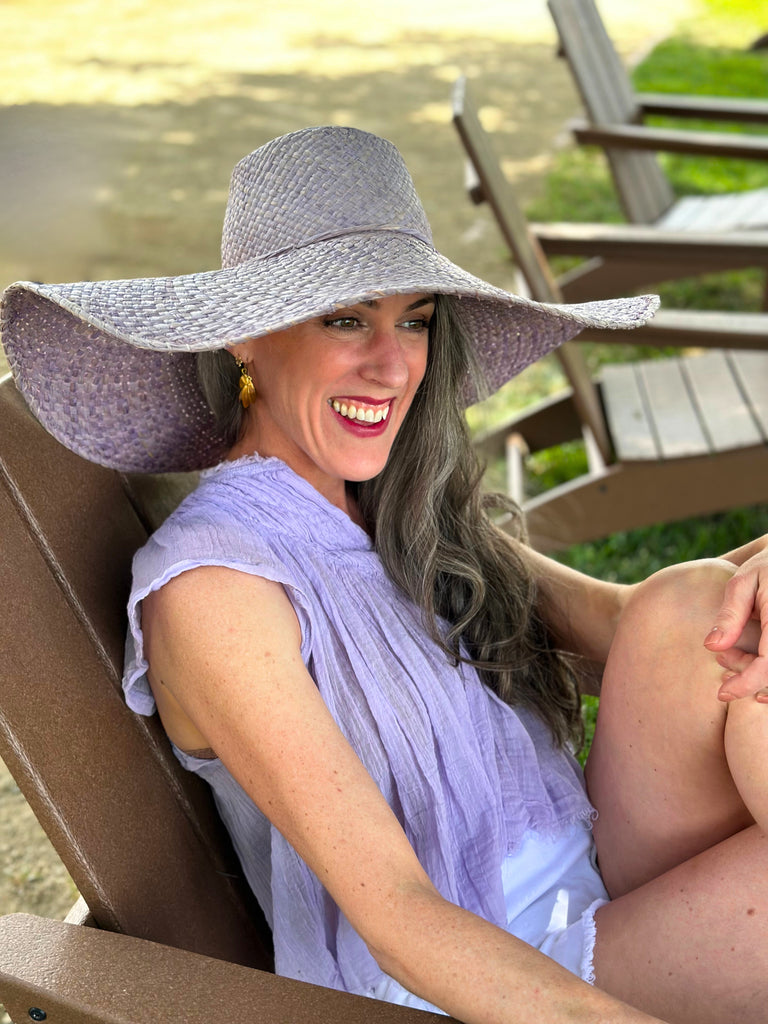 Model wearing 7" Brim Natasha Wisteria Woven XL Straw Sun Hat handmade woven natural raffia palm fiber in a solid hue of wisteria/lavender/lilac pink/purple with matching adjustable twisted raffia hat band and and extra wide brim - Shebobo