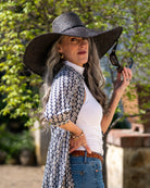 Model wearing 7" Wide Brim Natasha Black Woven XL Straw Sun Hat handmade woven natural raffia palm fiber in a solid hue of black with matching adjustable twisted raffia hat band and and extra wide brim - Shebobo