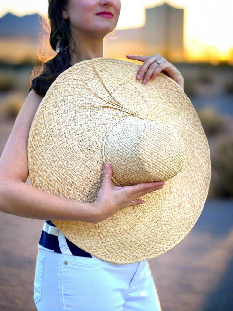 Model wearing 7" Wide Brim Natasha Natural Woven XL Straw Sun Hat handmade woven natural raffia palm fiber in a solid hue of straw color with matching adjustable twisted raffia hat band and and extra wide brim - Shebobo