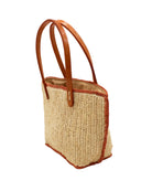 Side view Adele Mini Crochet Raffia Straw Handbag Purse with Colored Edge Natural & Blush handmade crochet raffia palm fiber in a solid hue of natural straw color with contrasting narrow band of blush orange/pink around the outer edges of the bag with subtle vertical band texture and leather handles - Shebobo