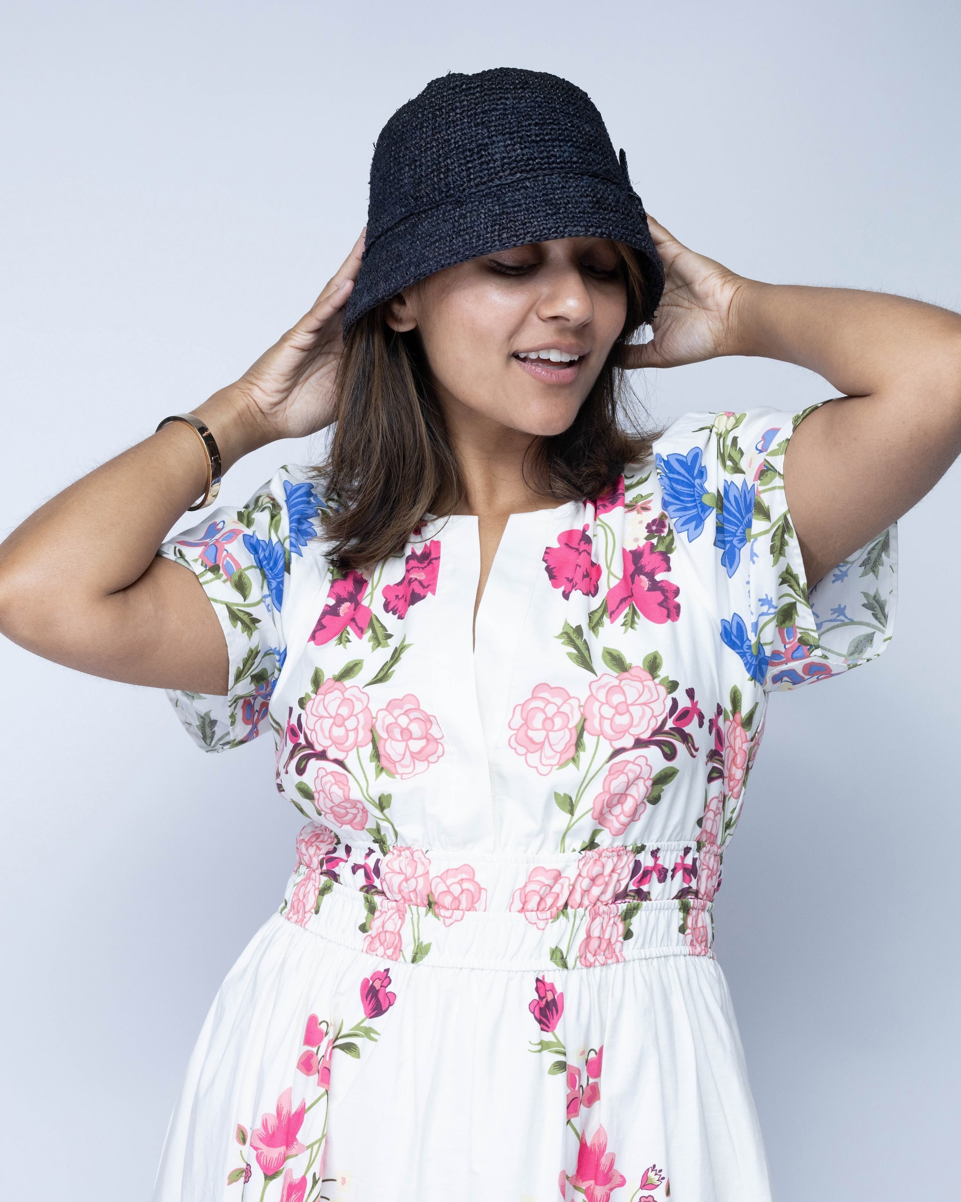 Model wearing Ali 2" Brim Crochet Bucket Raffia Straw Hats handmade natural raffia palm fiber in a subtle crochet link texture spiraling out from the top crown of the hat to the edge of the brim in a solid hue of black with matching braided adjustable hat band sun hat - Shebobo