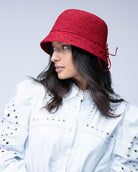 Model wearing Ali 2" Brim Crochet Bucket Raffia Straw Hats handmade natural raffia palm fiber in a subtle crochet link texture spiraling out from the top crown of the hat to the edge of the brim in a solid hue of red with matching braided adjustable hat band sun hat - Shebobo