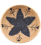 Detail view Amara Raffia Straw Decor Display Basket Bowls: Set of 3 handmade woven natural raffia palm fiber in a crochet loop technique concentric coiled circular pattern with centered black star or flower in the bottom of the bowl that goes up the cinnamon/tobacco/brown sides with matching black flower/arrow pattern on sides set of small, medium, and large straw display bowls - Shebobo