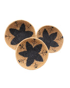 Amara Raffia Straw Decor Display Basket Bowls: Set of 3 handmade woven natural raffia palm fiber in a crochet loop technique concentric coiled circular pattern with centered black star or flower in the bottom of the bowl that goes up the cinnamon/tobacco/brown sides with matching black flower/arrow pattern on sides set of small, medium, and large straw display bowls - Shebobo