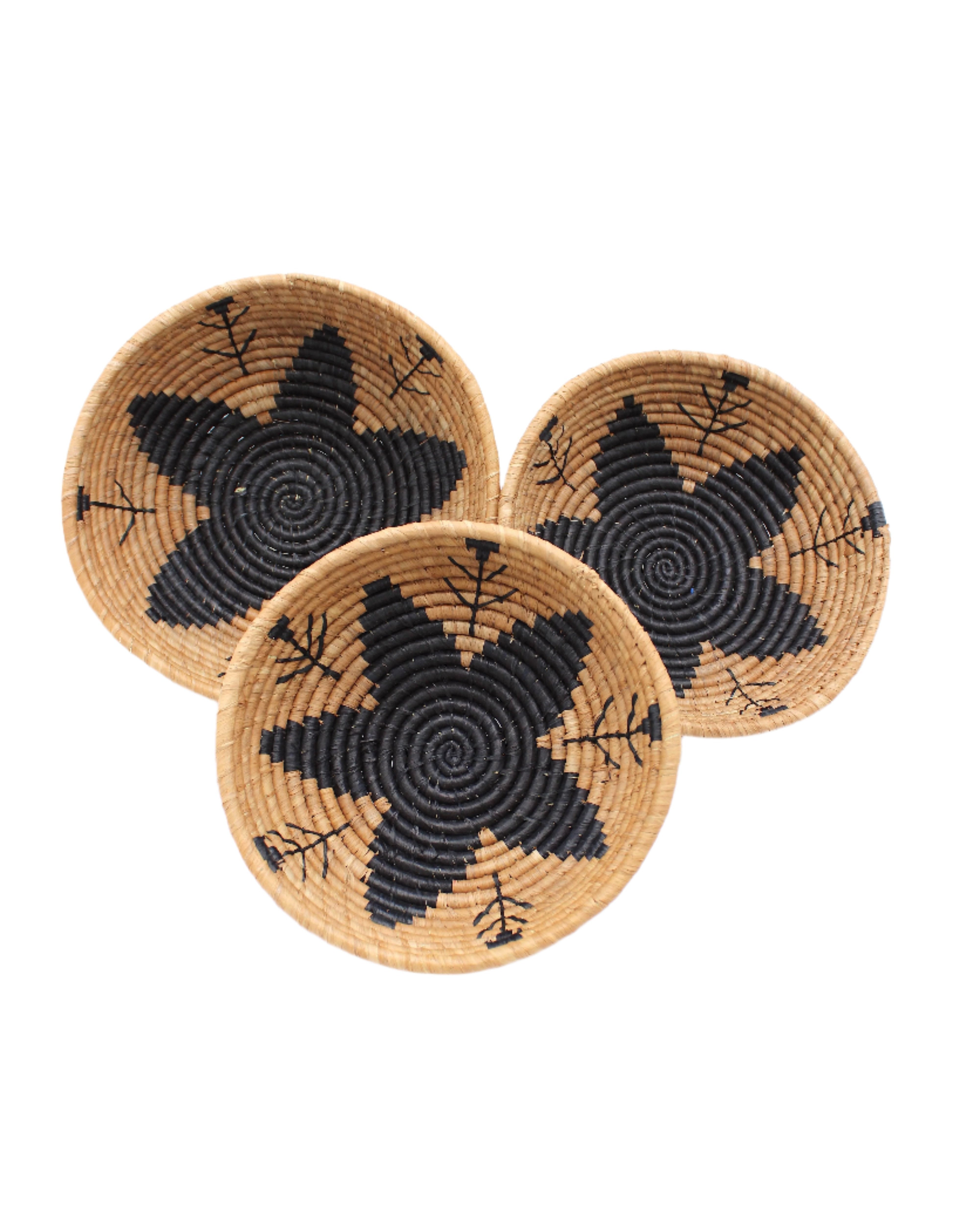 Amara Raffia Straw Decor Display Basket Bowls: Set of 3 handmade woven natural raffia palm fiber in a crochet loop technique concentric coiled circular pattern with centered black star or flower in the bottom of the bowl that goes up the cinnamon/tobacco/brown sides with matching black flower/arrow pattern on sides set of small, medium, and large straw display bowls - Shebobo