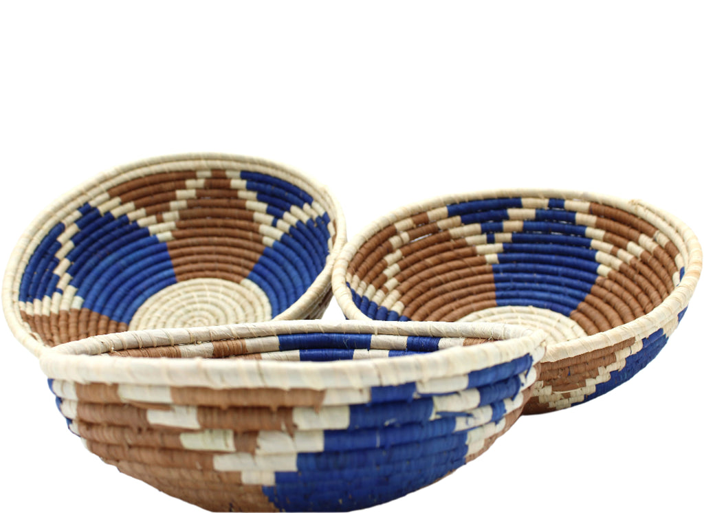 Side view Amara Raffia Straw Decor Display Basket Bowls: Set of 3 handmade woven natural raffia palm fiber in a crochet loop technique concentric coiled circular pattern with natural straw color centered in the bottom with blue, cinnamon/tobacco/brown, and natural geometric floral design pattern up the sides of the bowls set of small, medium, and large straw display bowls - Shebobo