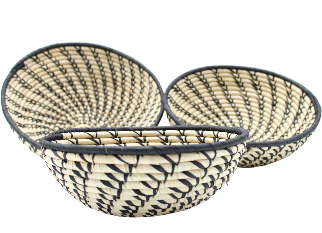 Side view Amara Raffia Straw Decor Display Basket Bowls: Set of 3 handmade woven natural raffia palm fiber in a crochet loop technique concentric coiled circular pattern with natural straw color centered in the bottom and that go up the sides of the bowls with contrasting black swirl stitch pattern and matching black rim/edge set of small, medium, and large straw display bowls - Shebobo