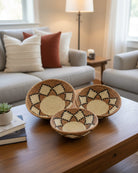 Lifestyle view Amara Raffia Straw Decor Display Basket Bowls: Set of 3 handmade woven natural raffia palm fiber in a crochet loop technique concentric coiled circular pattern with natural straw color centered in the bottom with cinnamon/tobacco/brown sides and natural diamond with black edges pattern set of small, medium, and large straw display bowls - Shebobo