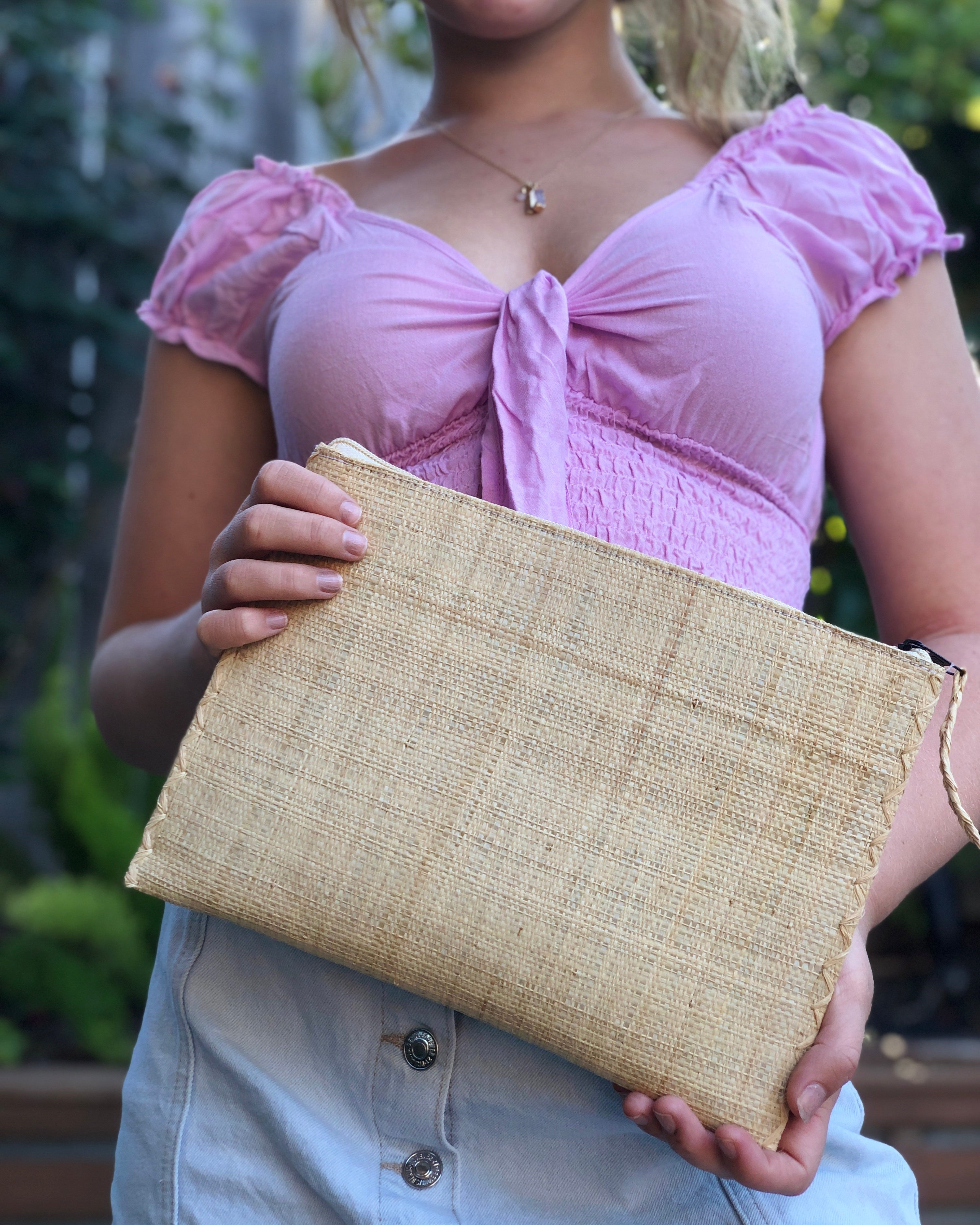 Model wearing Amelia size large of Set of 3 Natural straw color Nesting Zippered Straw Clutches Solid Colors handmade loomed raffia in a solid hue with matching zipper and braided zipper pull with cross stitch edging in three sizes of small, medium, and large - Shebobo
