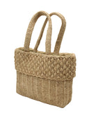 Side view Anna Petal Pattern Crochet Straw Basket Handbag handmade natural raffia palm fiber in a solid hue of Natural straw color crochet in multiple textures resulting in a subtle pattern of vertical linked bands on the bottom 2/3 of the bag, and a floral petal or shell pattern on the upper third with rolled panel of links making up the handles Beach Bag Purse - Shebobo