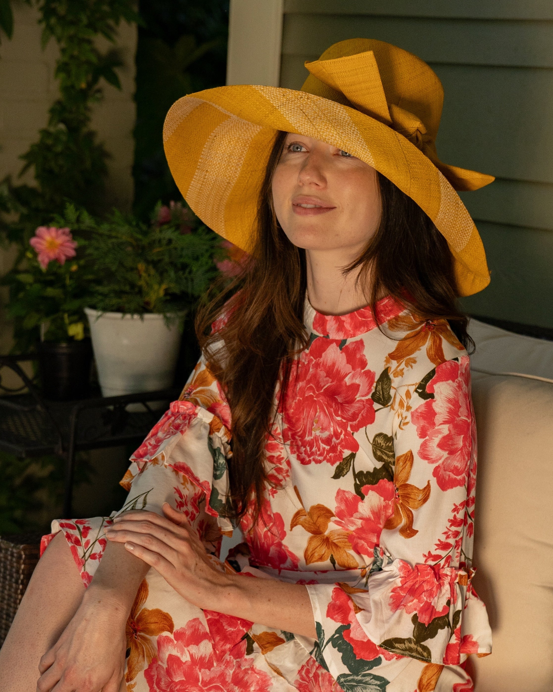 Model wearing Audrey 5" Wide Brim Saffron Two Tone Wide Stripe Straw Sun Hats with Big Bow handmade loomed raffia palm fiber in a solid hue of Saffron yellow/orange on the crown and matching oversized big bow embellishment hat band, with two tone even width wide stripe pattern of saffron and natural straw color that creates a swirl patterned brim - Shebobo