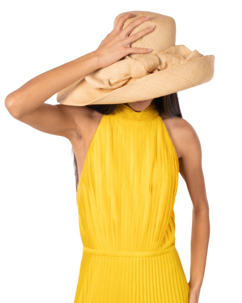 Model wearing Audrey 7" Wide Brim Solid Color Straw Sun Hats with Big Bow handmade loomed natural raffia straw fiber in a solid hue of natural straw color with matching oversized big bow embellishment hat band - Shebobo