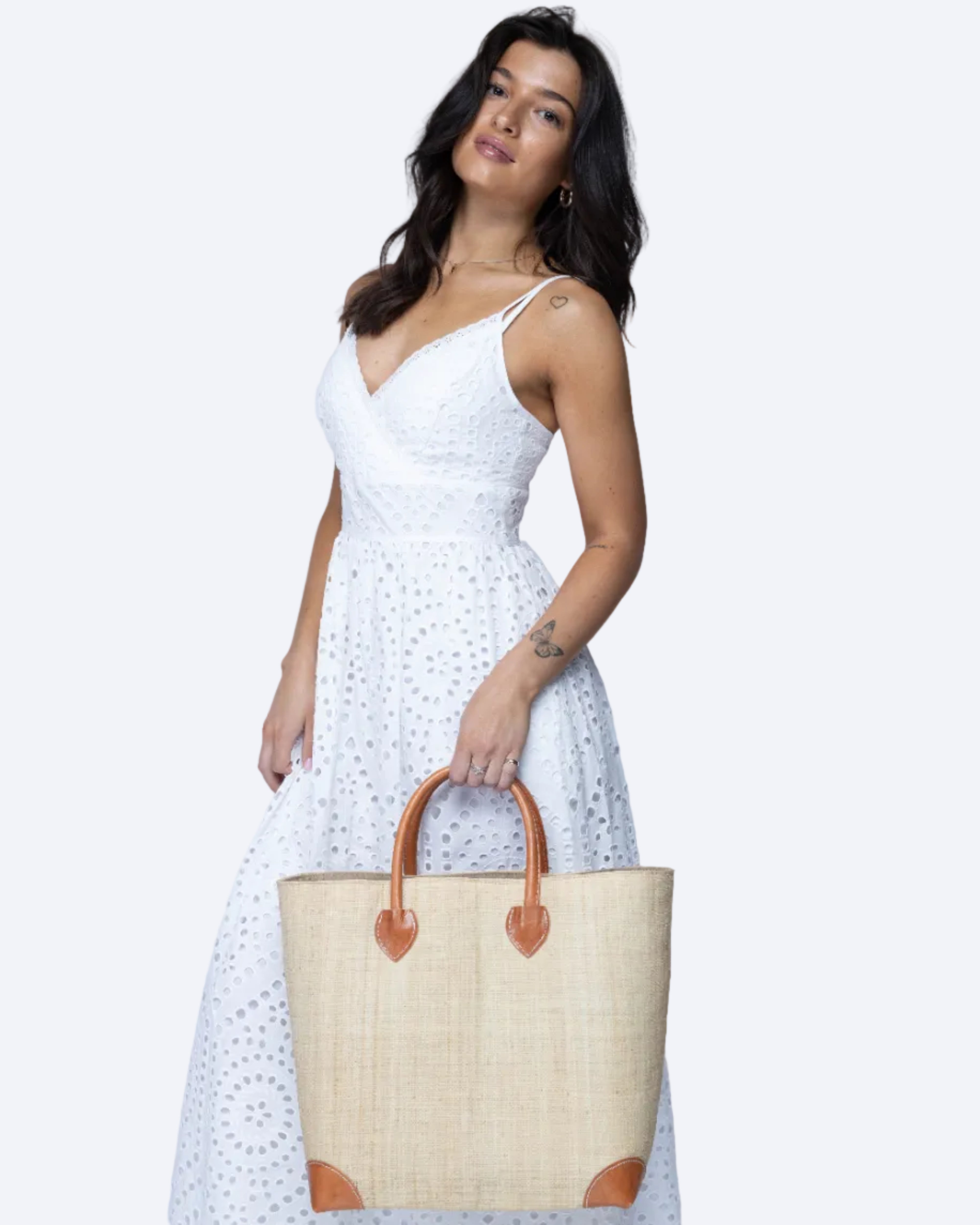 Model wearing Large Augustine Straw Basket Bag Natural handmade loomed raffia palm fiber in a solid hue of natural straw color handbag purse with leather accents and handles beach bag - Shebobo