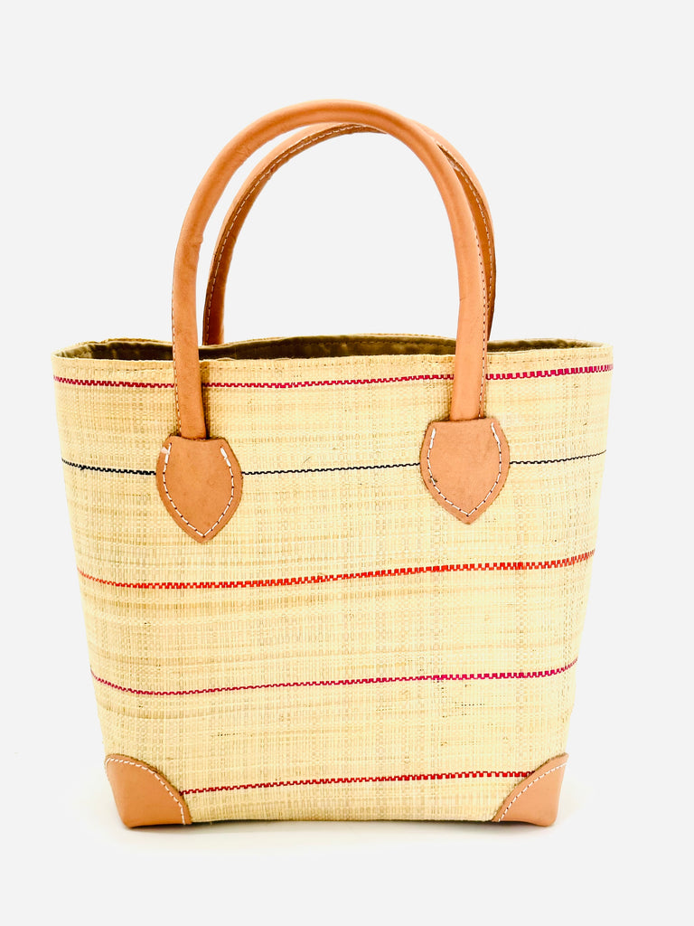 Augustine pinstripes straw basket bag handmade loomed raffia in natural wide horizontal bands with multicolor coral red/orange, fuchsia pink, and navy blue small bands running through in a stripe pattern with leather accents and handles handbag purse - Shebobo