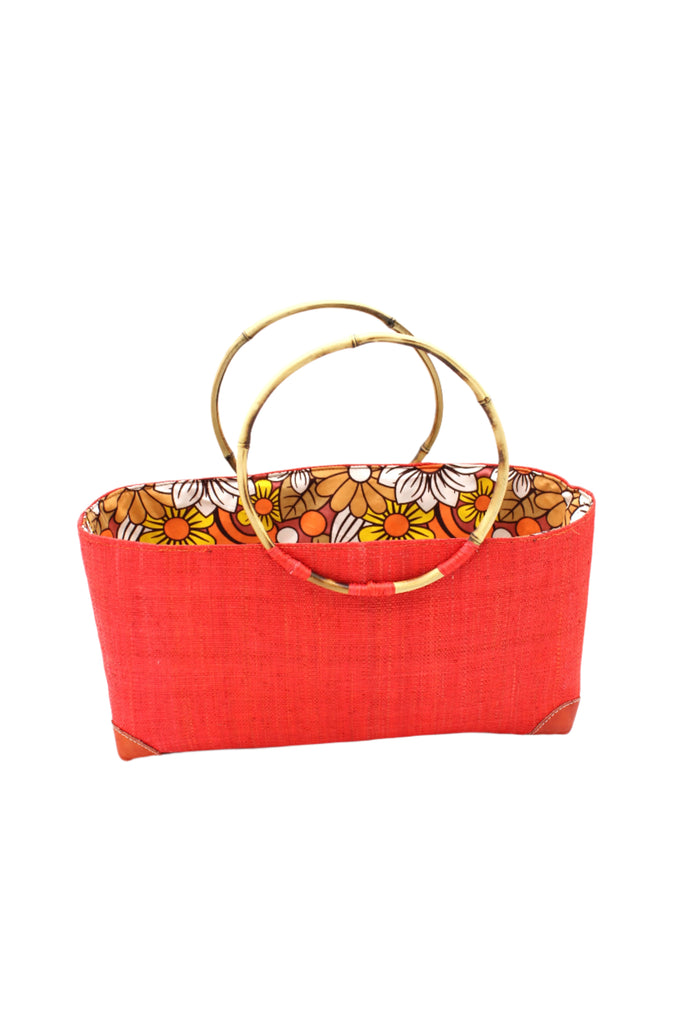 Bebe Straw Handbag with Bamboo Handle handmade loomed natural raffia palm fiber in a solid hue of coral orange/red with molded circular bamboo handles, leather feet, and assorted print African wax-cloth fabric liner - Shebobo