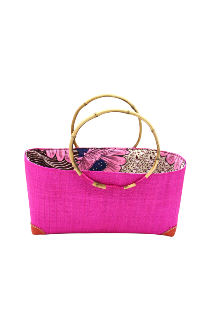 Bebe Straw Handbag with Bamboo Handle handmade loomed natural raffia palm fiber in a solid hue of fuchsia bright/hot/barbie/pink with molded circular bamboo handles, leather feet, and assorted print African wax-cloth fabric liner - Shebobo