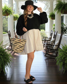 Model wearing Bimini Crochet Straw Shoulder Bag Purse with Zebra Stripe handmade natural raffia palm fiber in a two tone zebra stripe of primarily Natural straw color with small horizontal asymmetrical bands of Black that create spotted stripe pattern with leather handles handbag beach bag purse - Shebobo (with Bolero 3" Brim Crochet Straw Sun Hats)