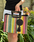 Model wearing Lace Pattern Dreamcatcher Crochet Raffia Straw Tassel Charm Embellishment handmade natural raffia palm fiber in a solid hue of Black in a woven lace style disc with two concentric rings of open circular pattern in the center and scalloped outer edge with matching twist loop and brushed fringe tassel - Shebobo