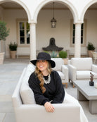 Model wearing 3" Brim Bolero Crochet Straw Sun Hats handmade crochet natural raffia palm fiber in a solid hue of black making a concentric pattern from the center top of the flattened crown spiraling out to the edge of the brim with matching adjustable raffia braid hat band - Shebobo