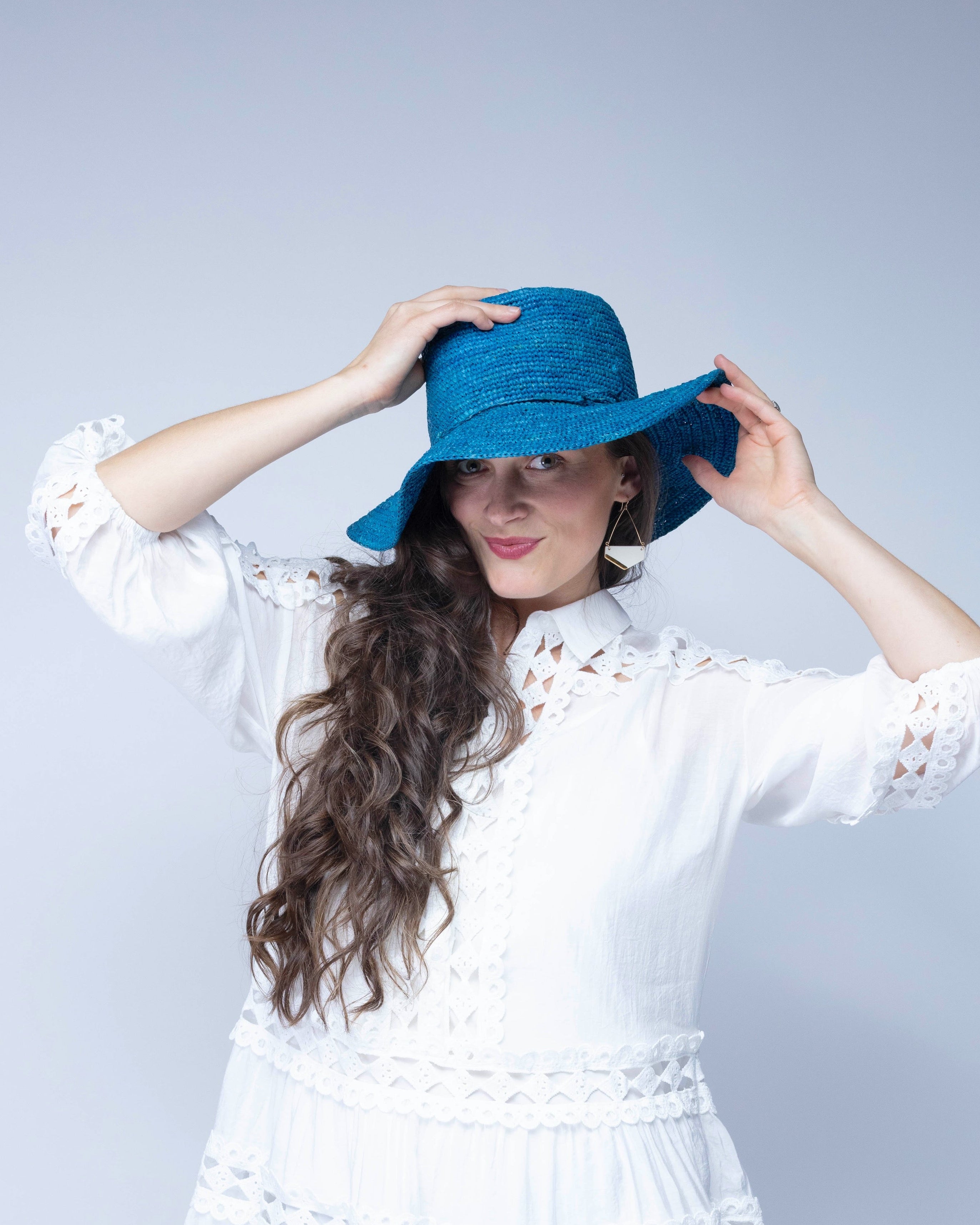 Model wearing 3" Brim Bolero Crochet Straw Sun Hats handmade crochet natural raffia palm fiber in a solid hue of turquoise blue/green making a concentric pattern from the center top of the flattened crown spiraling out to the edge of the brim with matching adjustable raffia braid hat band - Shebobo