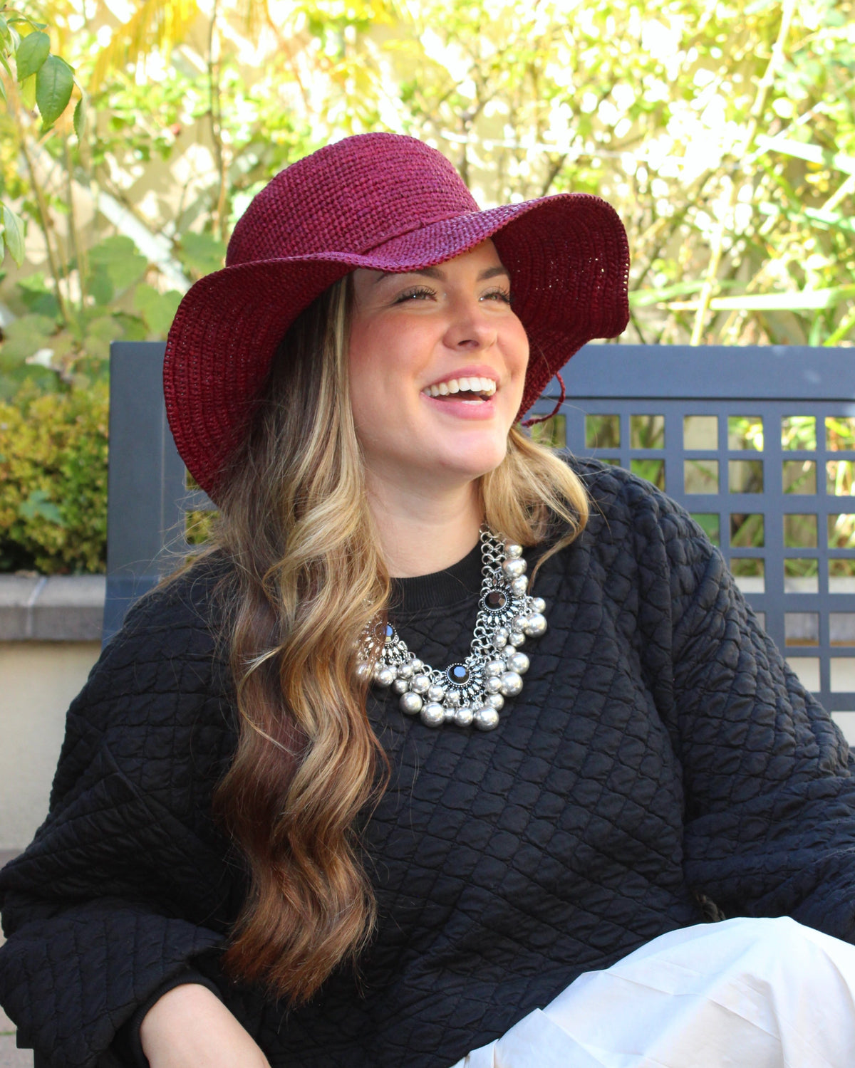Model wearing 3" Brim Bolero Crochet Straw Sun Hats handmade crochet natural raffia palm fiber in a solid hue of umberwine bordeaux/claret/deep/dark/red/purple making a concentric pattern from the center top of the flattened crown spiraling out to the edge of the brim with matching adjustable raffia braid hat band - Shebobo