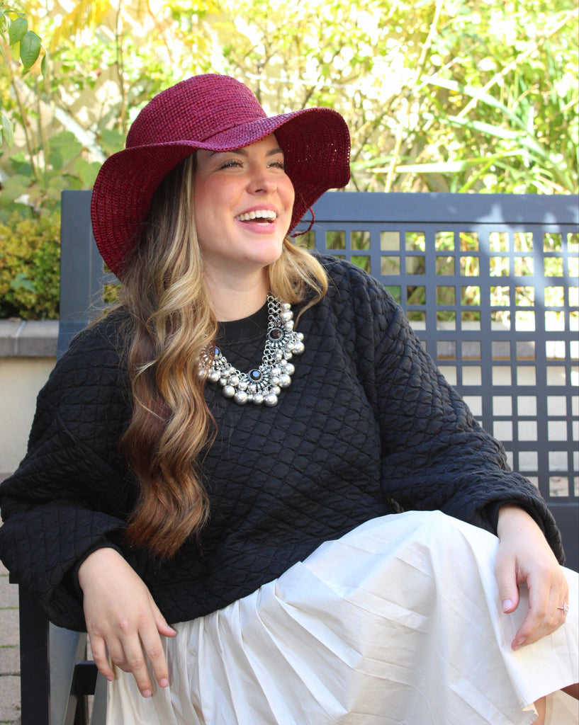 Model wearing 3" Brim Bolero Crochet Straw Sun Hats handmade crochet natural raffia palm fiber in a solid hue of umberwine bordeaux/claret/deep/dark/red/purple making a concentric pattern from the center top of the flattened crown spiraling out to the edge of the brim with matching adjustable raffia braid hat band - Shebobo