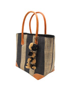 Side view Bora Bora Black Two Tone Stripes Straw Basket Bag with Waterfall Pompoms Charm Embellishment handmade loomed natural raffia palm fiber in a multicolor horizontal stripe pattern of even width wide bands of black and natural straw color with leather handles and feet plus matching waterfall pompom charm embellishment handbag beach bag - Shebobo