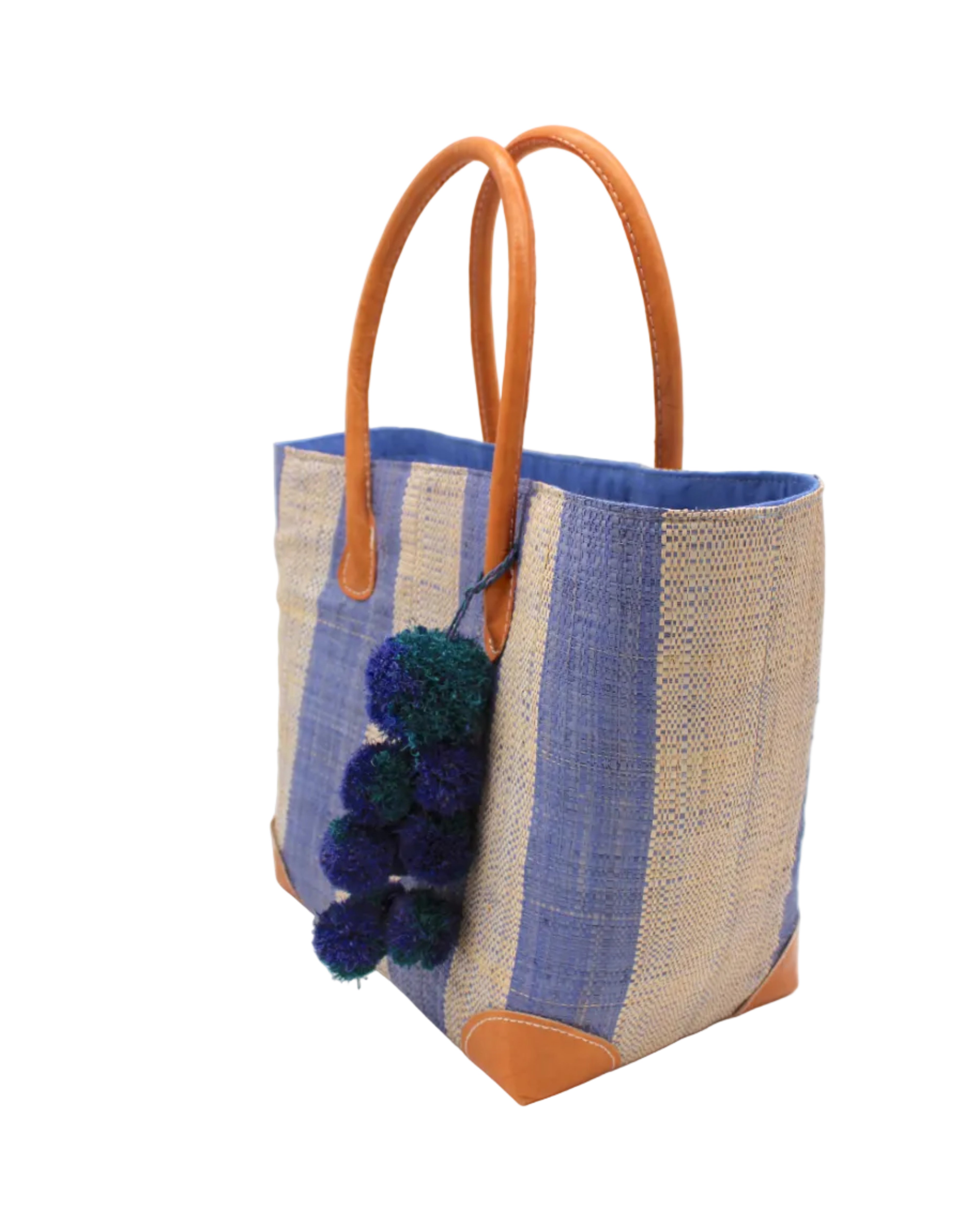 Side view Bora Bora Denim Two Tone Stripes Straw Basket Bag with Waterfall Pompoms Charm Embellishment handmade loomed natural raffia palm fiber in a multicolor horizontal stripe pattern of even width wide bands of denim retro/light/blue and natural straw color with leather handles and feet plus matching waterfall pompom charm embellishment handbag beach bag - Shebobo