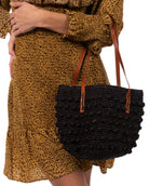Model wearing Boucle Black Crochet Small Straw Handbag  handmade woven raffia palm fiber in a solid hue of black in a supple nub/ball texture of horizontal bands around the bag with link weave around the top plus assorted print drawstring liner and leather handles  shoulder bag purse - Shebobo