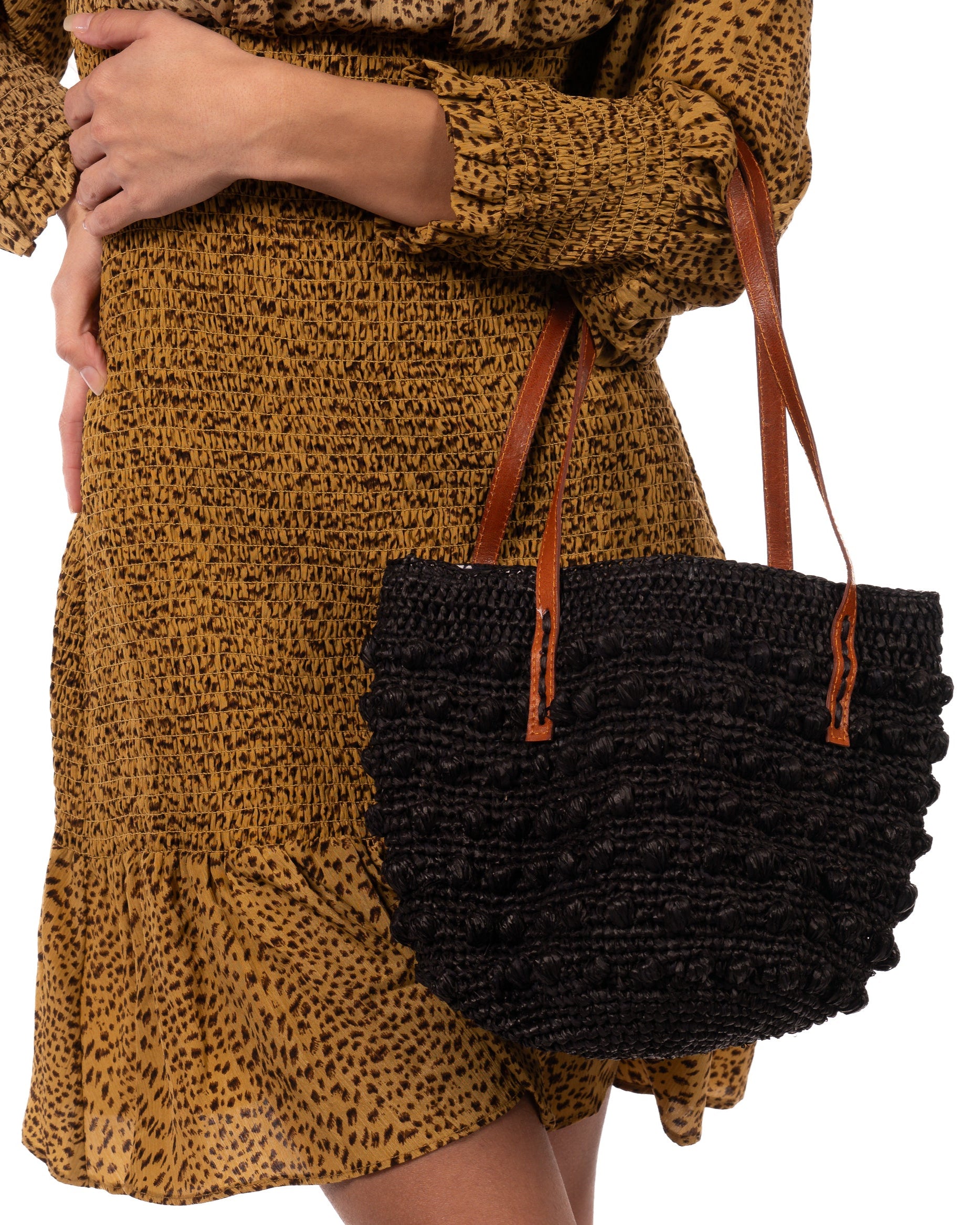 Model wearing Boucle Black Crochet Small Straw Handbag  handmade woven raffia palm fiber in a solid hue of black in a supple nub/ball texture of horizontal bands around the bag with link weave around the top plus assorted print drawstring liner and leather handles  shoulder bag purse - Shebobo