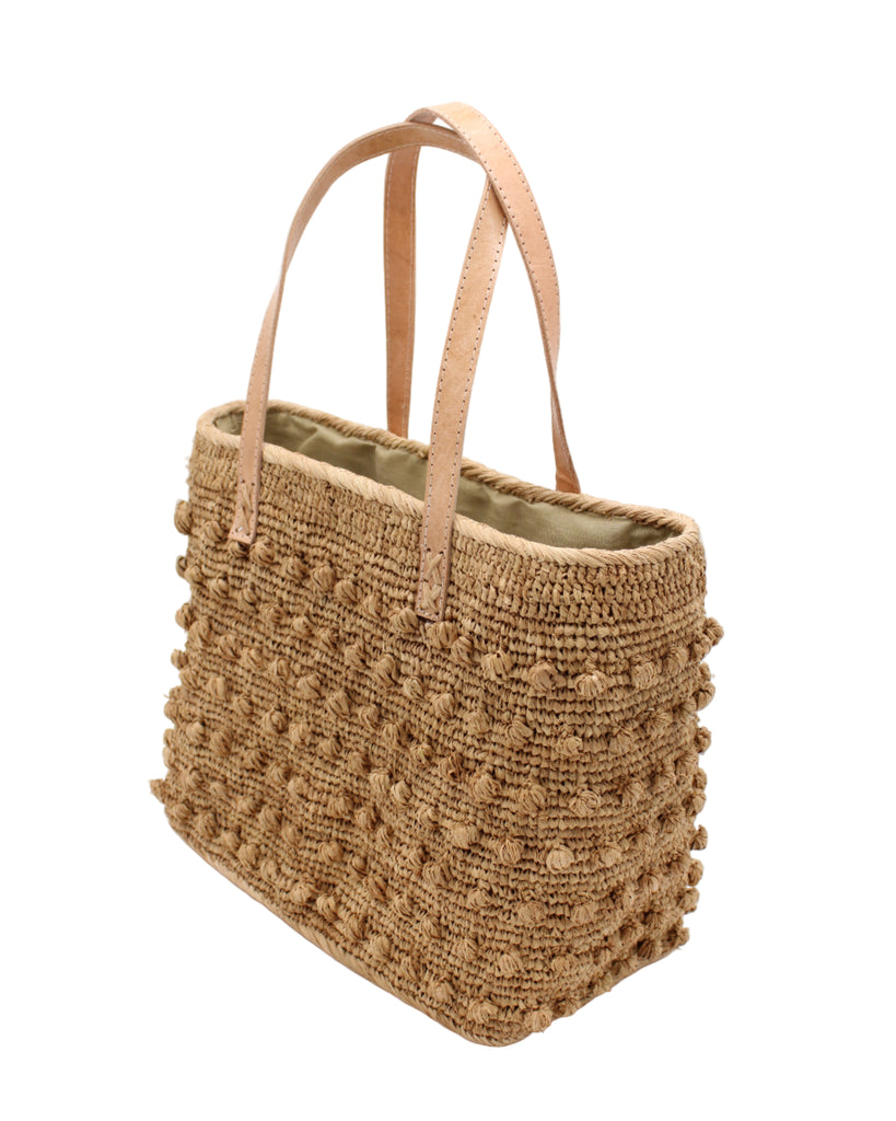Side view Boucle Cappuccino Crochet Straw Basket Bag handmade woven raffia palm fiber in a solid hue of cappuccino tea/light/brown in a supple nub/ball texture of horizontal bands around the bag with link weave around the top and loop crochet edging on the bottom and top plus leather handles beach bag shoulder bag purse - Shebobo
