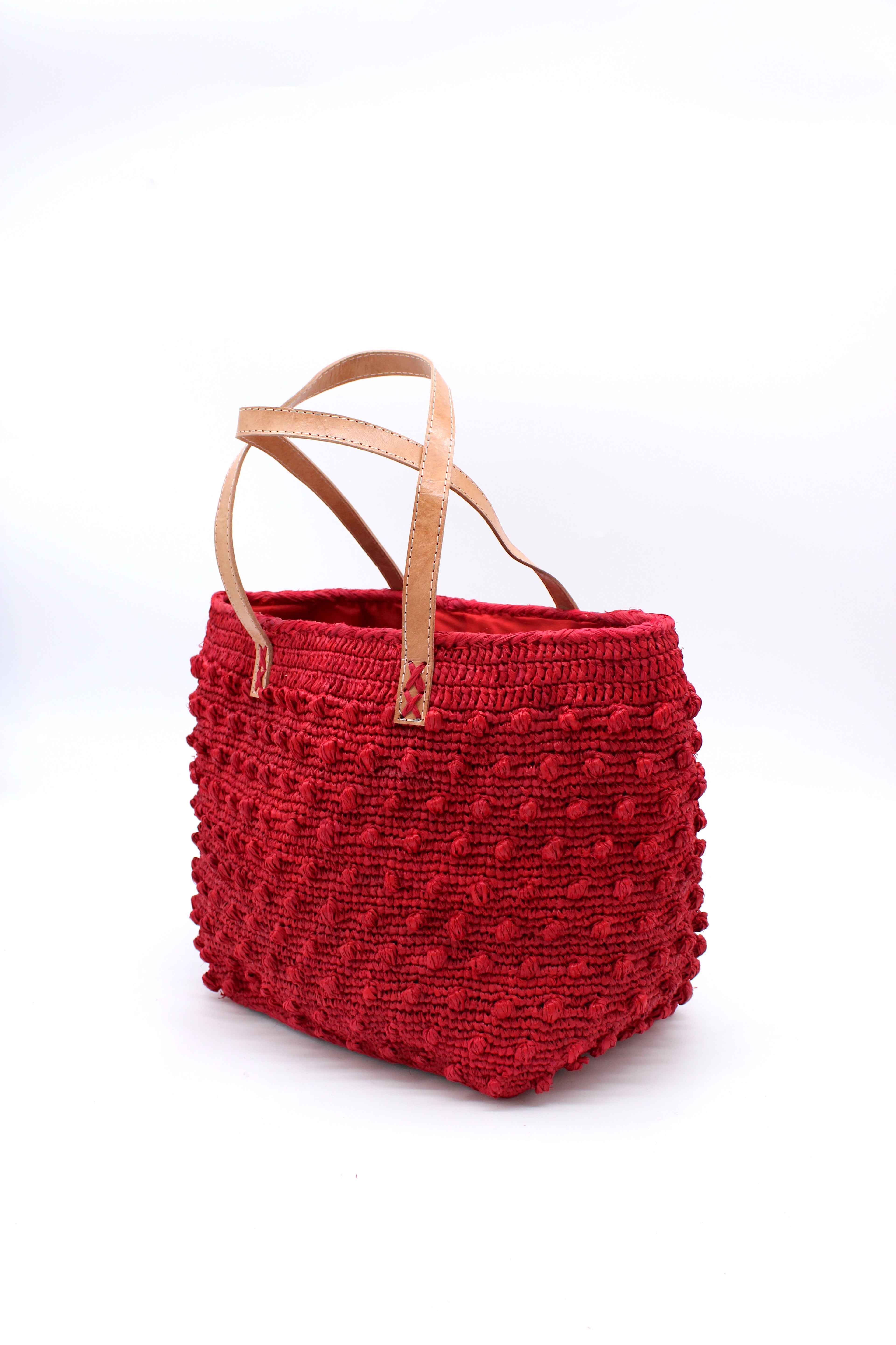 Side view Boucle Red Crochet Straw Basket Bag handmade woven raffia palm fiber in a solid hue of red in a supple nub/ball texture of horizontal bands around the bag with link weave around the top and loop crochet edging on the bottom and top plus leather handles beach bag shoulder bag purse - Shebobo