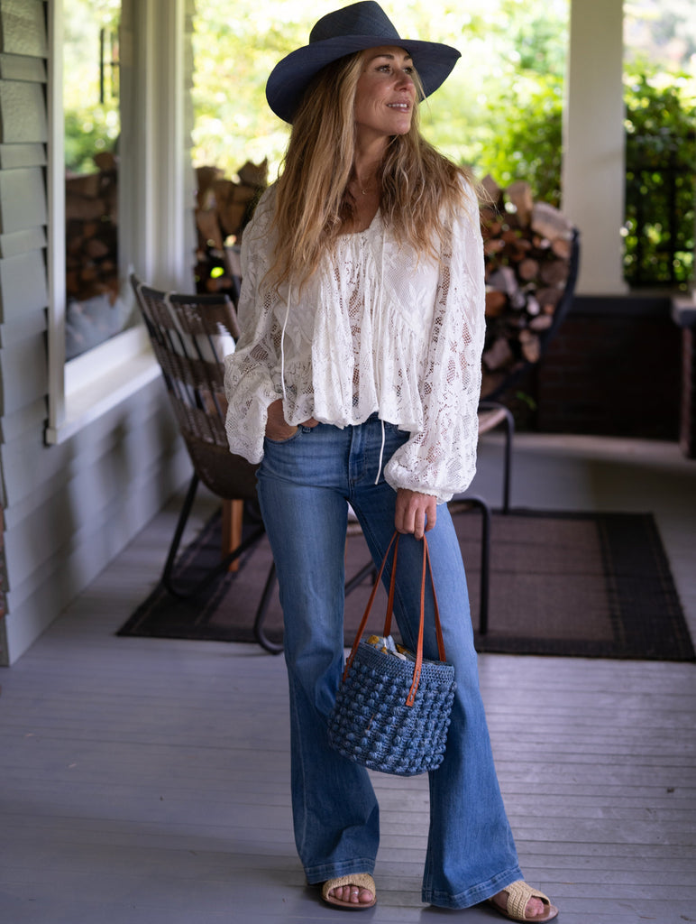 Model wearing Boucle Denim Crochet Small Straw Handbag  handmade woven raffia palm fiber in a solid hue of denim retro/light/blue in a supple nub/ball texture of horizontal bands around the bag with link weave around the top plus assorted print drawstring liner and leather handles  shoulder bag purse - Shebobo (with Panama Unisex Straw Hats)