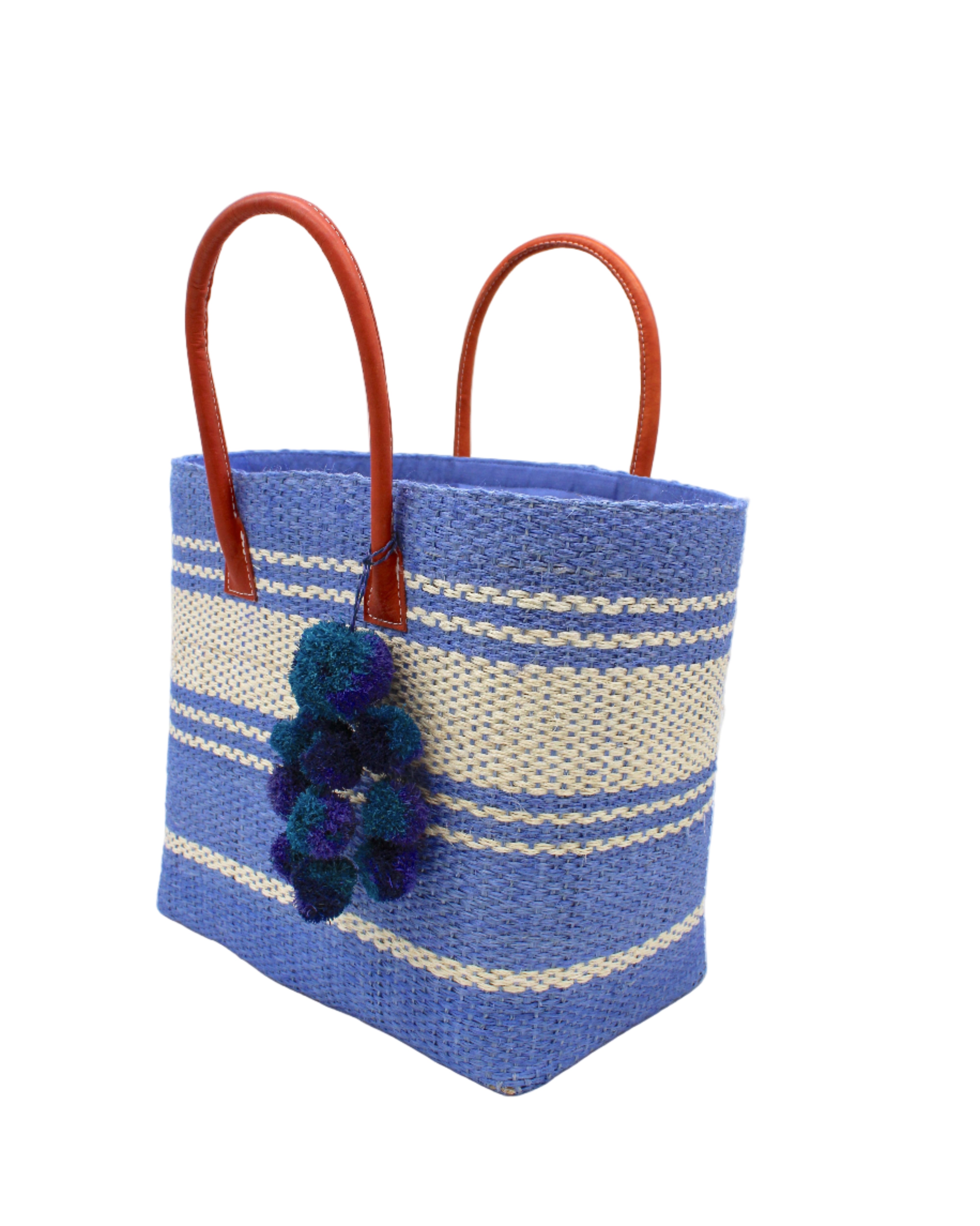Side view Cabrillo Sisal Basket Bag with Waterfall Pompoms Charm Embellishment handmade natural sisal fiber woven into a multicolor two tone Denim retro/light/blue and natural straw color  horizontal stripe pattern with muti-width bands of color plus leather handles and multicolor raffia  charm shoulder bag beach bag - Shebobo