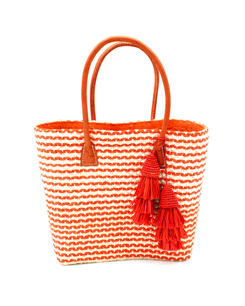Cancun Small Sisal Basket Bag with Tassel Charm handmade natural sisal fibers woven into even width horizontal bands of coral orange and natural straw color that create a pinstripe pattern with matching knotted raffia tufts tassel charm embellishment and leather handles beach bag - Shebob